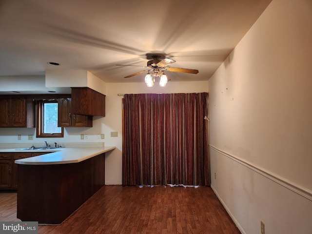 kitchen with dark hardwood / wood-style floors, dark brown cabinets, kitchen peninsula, and sink