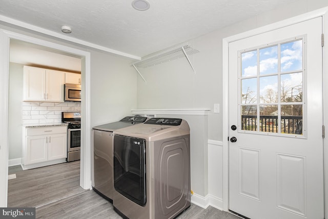 clothes washing area with separate washer and dryer and light hardwood / wood-style floors