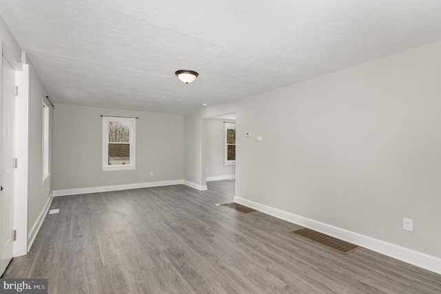 unfurnished room with a textured ceiling and dark hardwood / wood-style floors