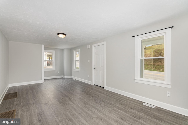 unfurnished room with a textured ceiling and dark hardwood / wood-style floors