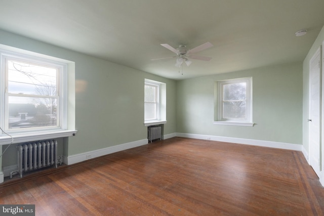 spare room featuring dark hardwood / wood-style flooring, a healthy amount of sunlight, and radiator