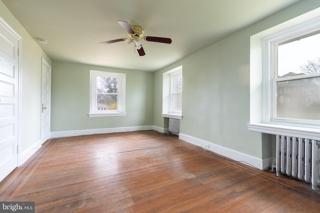 spare room with ceiling fan, dark wood-type flooring, and radiator heating unit