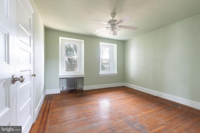 empty room with ceiling fan, radiator heating unit, and dark wood-type flooring