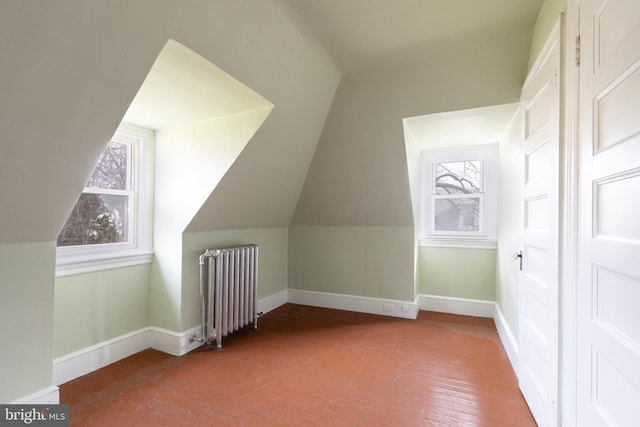 additional living space featuring vaulted ceiling, wood-type flooring, and radiator