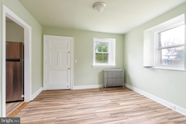 spare room featuring light hardwood / wood-style floors and radiator heating unit