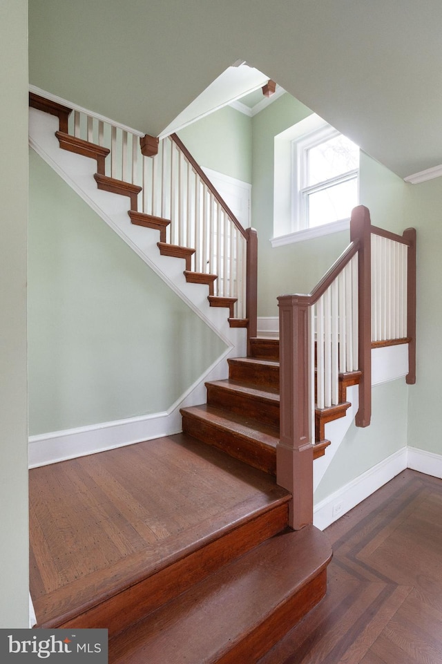 stairway featuring dark parquet floors and ornamental molding