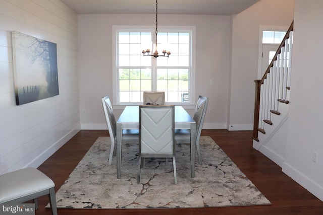 dining space featuring wood walls, dark hardwood / wood-style flooring, and a chandelier