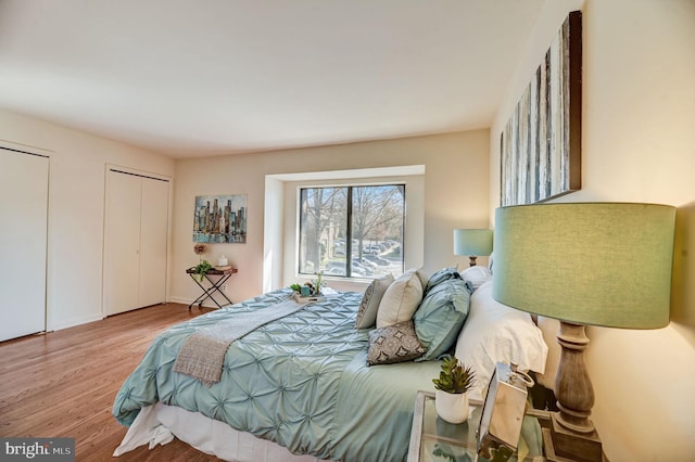 bedroom featuring two closets and light hardwood / wood-style floors