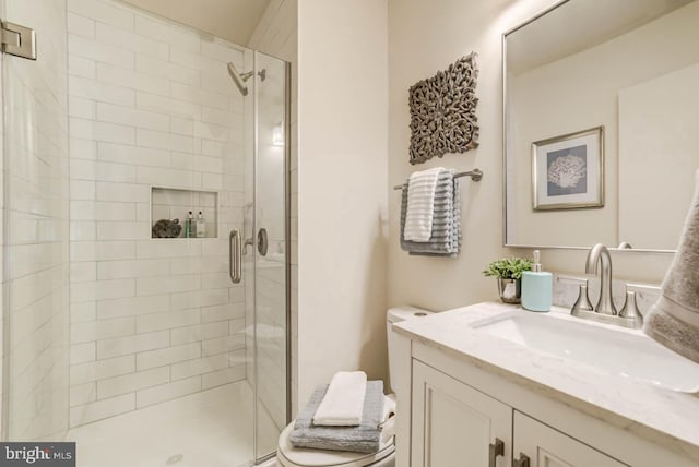 bathroom featuring a shower with shower door, toilet, and vanity