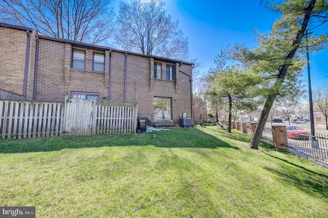 back of property featuring central air condition unit and a lawn