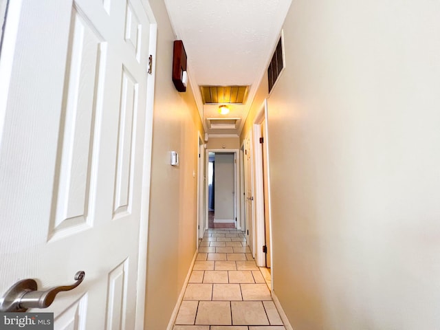 hall with a tray ceiling and light tile floors