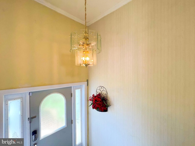 foyer with crown molding and an inviting chandelier