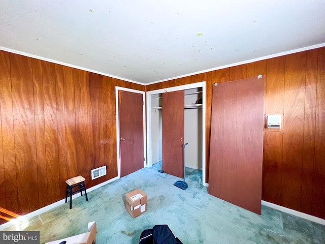 interior space with a closet, wood walls, and ornamental molding