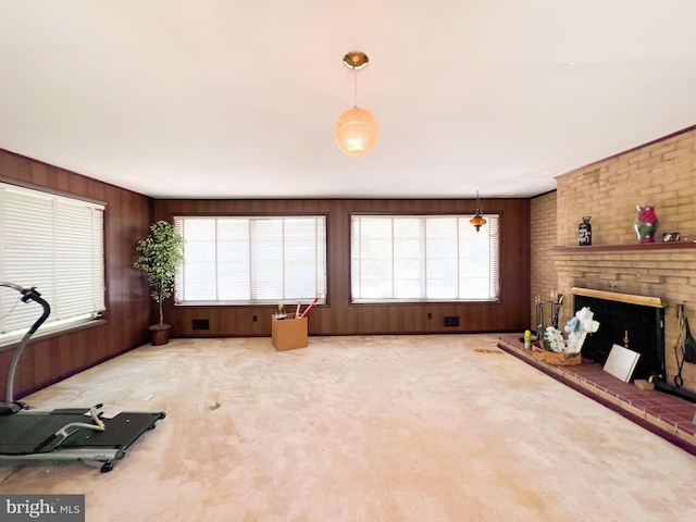 living room featuring plenty of natural light, a brick fireplace, carpet flooring, and wooden walls