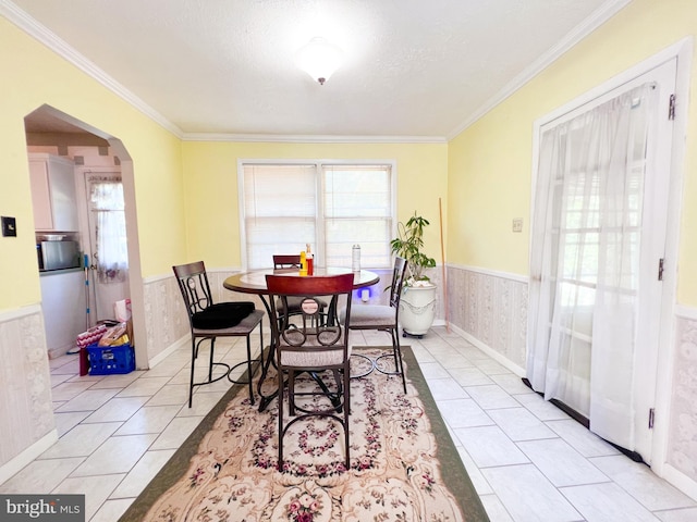 dining space with crown molding, a healthy amount of sunlight, and light tile floors