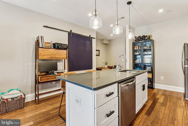 kitchen with dark hardwood / wood-style floors, an island with sink, sink, white cabinets, and a barn door