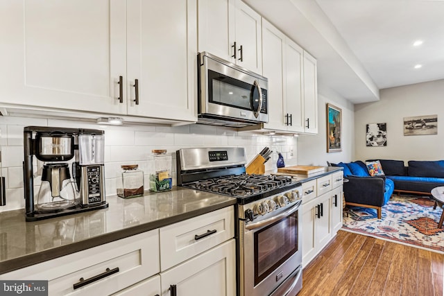 kitchen featuring stainless steel appliances, tasteful backsplash, white cabinetry, and dark hardwood / wood-style floors