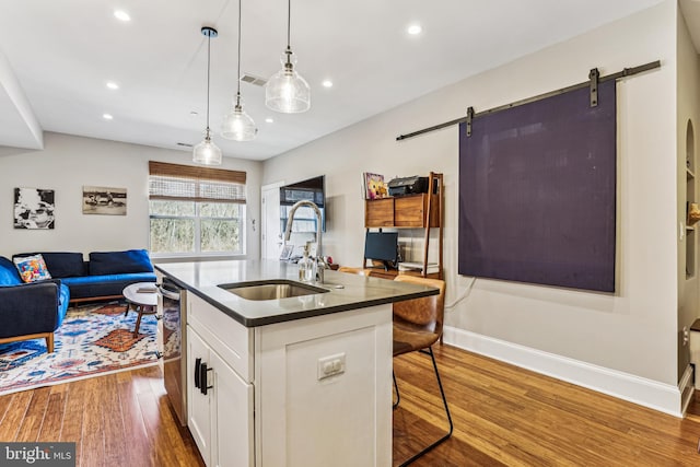 kitchen featuring hardwood / wood-style floors, sink, a barn door, and white cabinetry