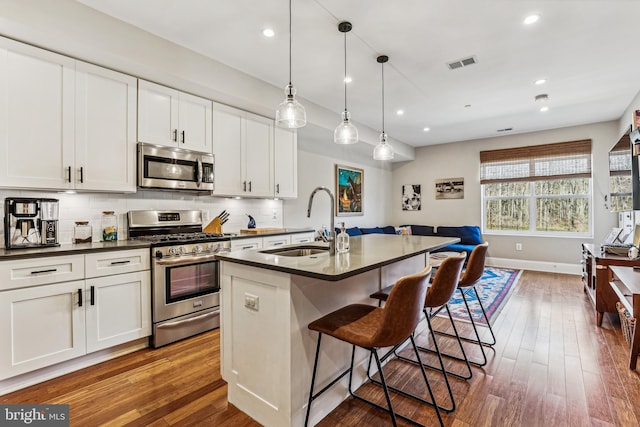 kitchen with white cabinetry, light hardwood / wood-style floors, tasteful backsplash, and stainless steel appliances