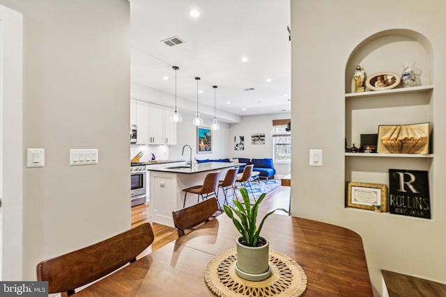 dining area with sink, built in shelves, and light hardwood / wood-style flooring