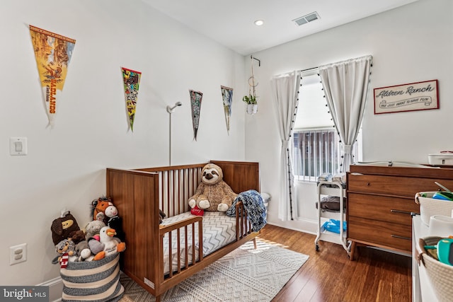 bedroom with dark hardwood / wood-style flooring and a crib