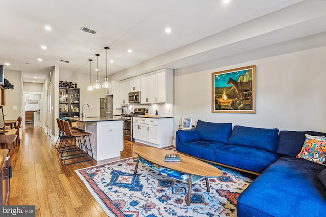 living room featuring sink and light hardwood / wood-style floors