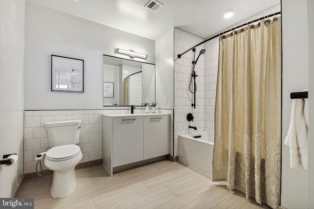 full bathroom with shower / bath combo, tile walls, toilet, tile floors, and oversized vanity