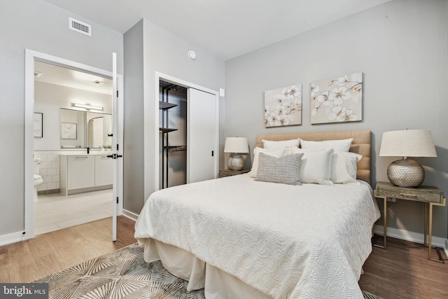 bedroom with light tile floors, ensuite bathroom, and a closet