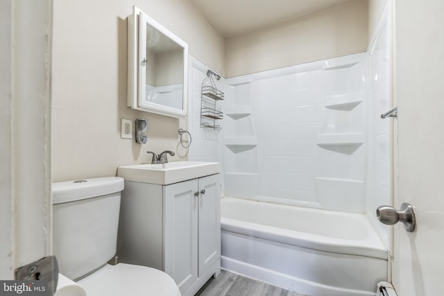 full bathroom featuring toilet, hardwood / wood-style floors, washtub / shower combination, and vanity