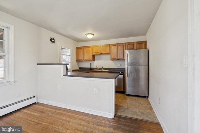 kitchen featuring kitchen peninsula, appliances with stainless steel finishes, a baseboard radiator, and wood-type flooring