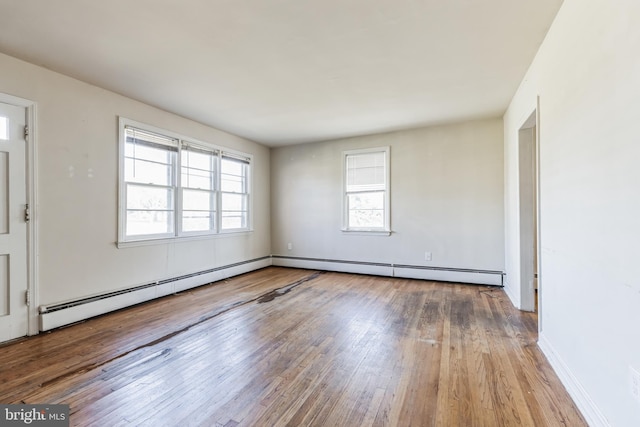 empty room featuring a baseboard heating unit and light hardwood / wood-style flooring