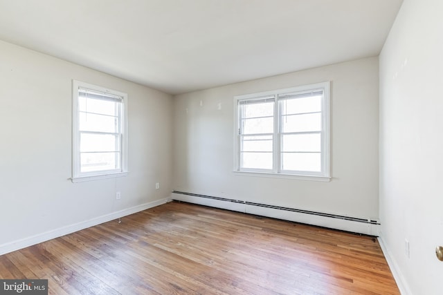 unfurnished room featuring a baseboard heating unit and light hardwood / wood-style flooring