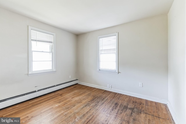 empty room with a baseboard heating unit, light hardwood / wood-style flooring, and a wealth of natural light