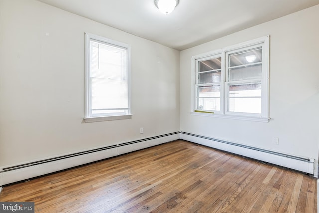 spare room featuring plenty of natural light, baseboard heating, and light hardwood / wood-style floors