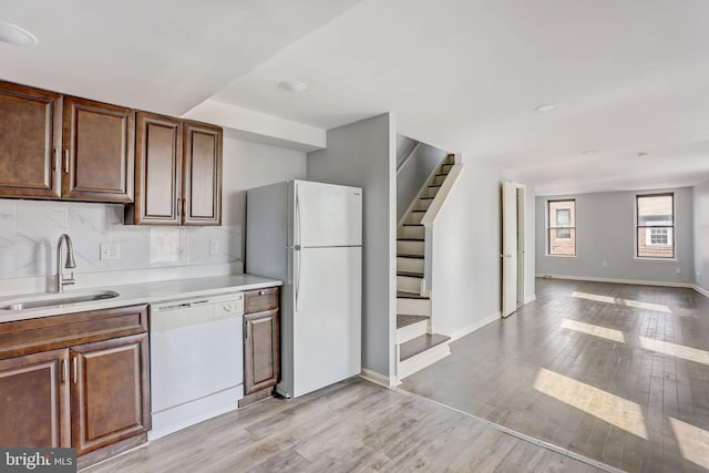 kitchen featuring backsplash, light hardwood / wood-style flooring, white appliances, and sink