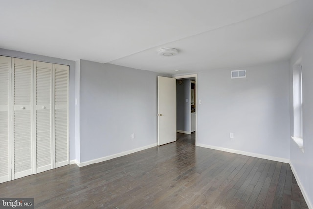 unfurnished bedroom with dark hardwood / wood-style floors and a closet