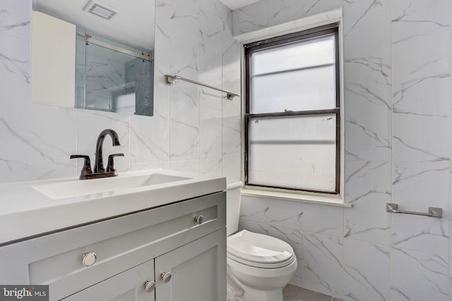 bathroom featuring tile walls, toilet, and vanity