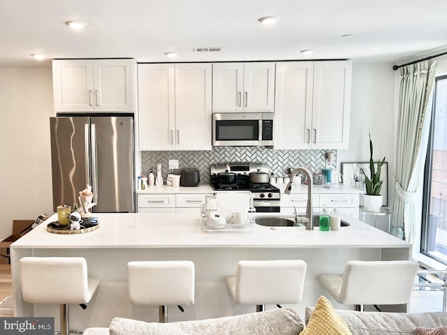 kitchen featuring a kitchen bar, appliances with stainless steel finishes, and white cabinetry