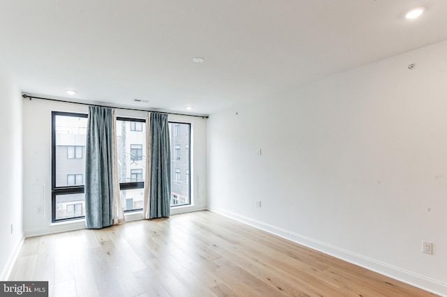 spare room featuring light hardwood / wood-style floors and plenty of natural light