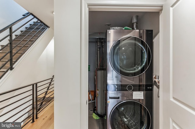 laundry area with light hardwood / wood-style flooring, gas water heater, and stacked washing maching and dryer