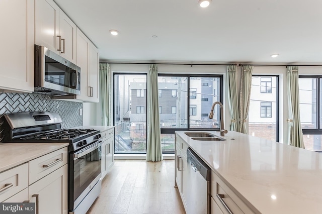 kitchen with sink, stainless steel appliances, backsplash, and white cabinets