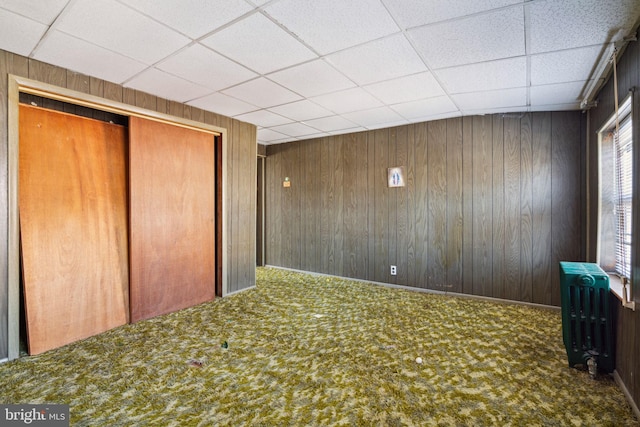 unfurnished bedroom featuring a closet, carpet, and wood walls