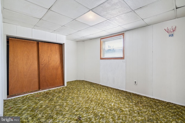 unfurnished bedroom featuring a closet, a drop ceiling, and carpet