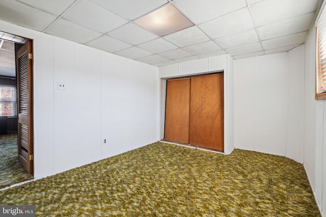 unfurnished bedroom featuring carpet, a closet, and a paneled ceiling