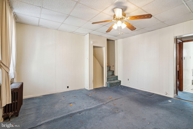 spare room featuring a paneled ceiling, dark carpet, ceiling fan, and radiator