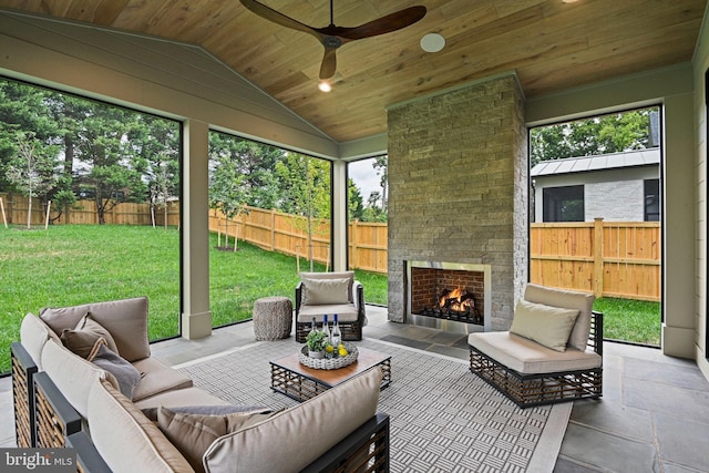 interior space with lofted ceiling, a wealth of natural light, wooden ceiling, and an outdoor stone fireplace