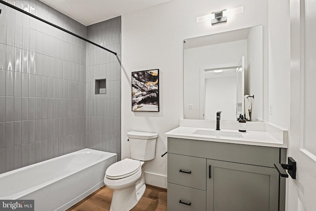 full bathroom with vanity, hardwood / wood-style flooring, toilet, and tiled shower / bath combo