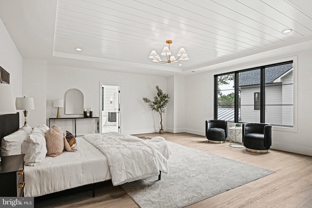 bedroom featuring a tray ceiling, a chandelier, and light hardwood / wood-style floors