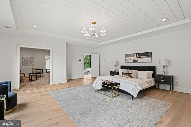 bedroom featuring a notable chandelier, a raised ceiling, and light wood-type flooring