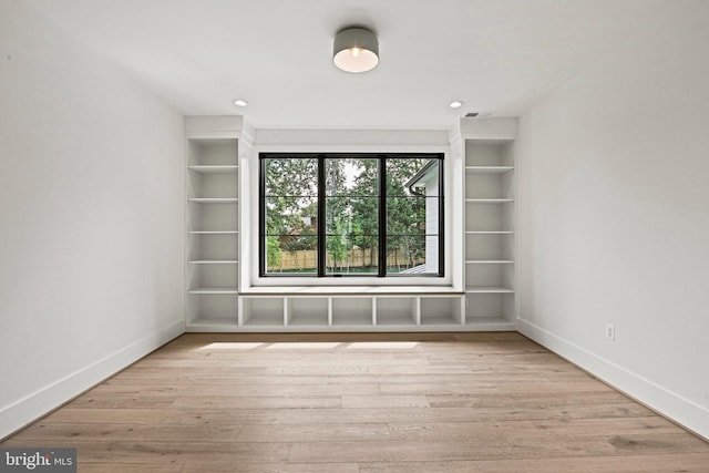 spare room with light hardwood / wood-style floors and built in shelves